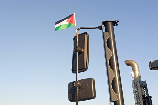 Palestine flag flying from the wing mirror of dockworker's truck