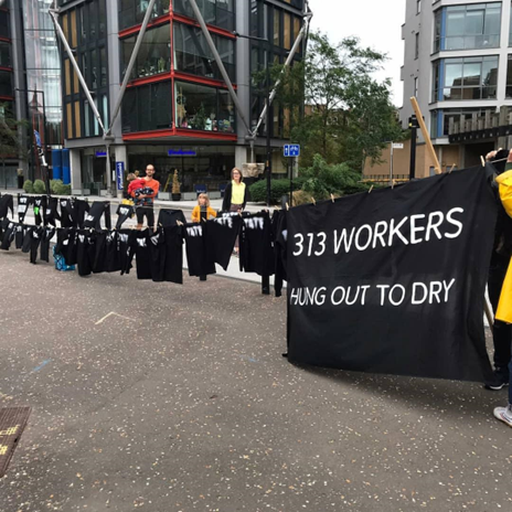Protest banner on washing line with Tate t-shirts. Banner says "313 workers - hung out to dry"